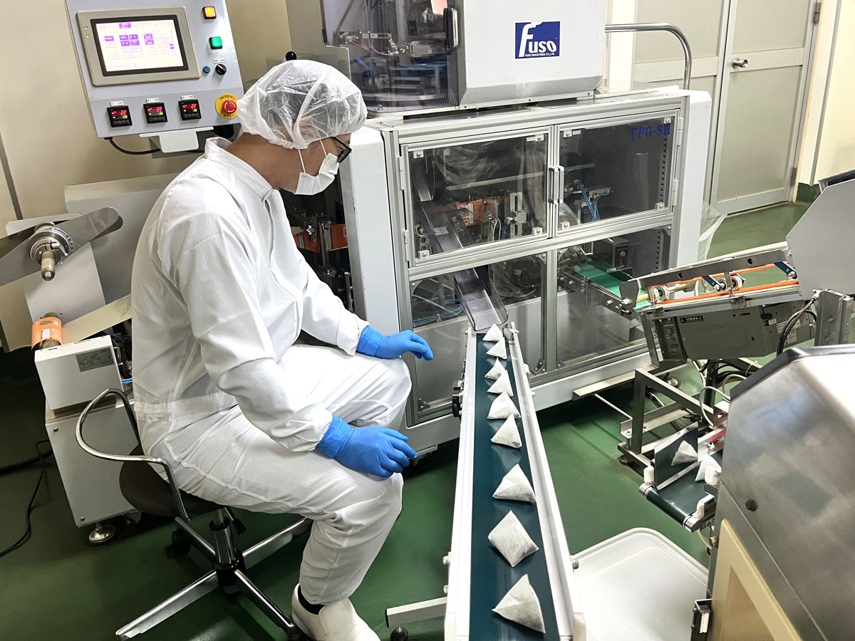 製造機の前に座り、ティーバッグを目視で確認するスタッフ