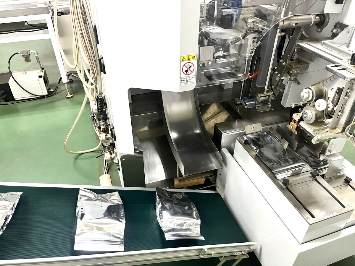 アルミのパッケージに袋詰めする機械と、並んだ柿茶の袋